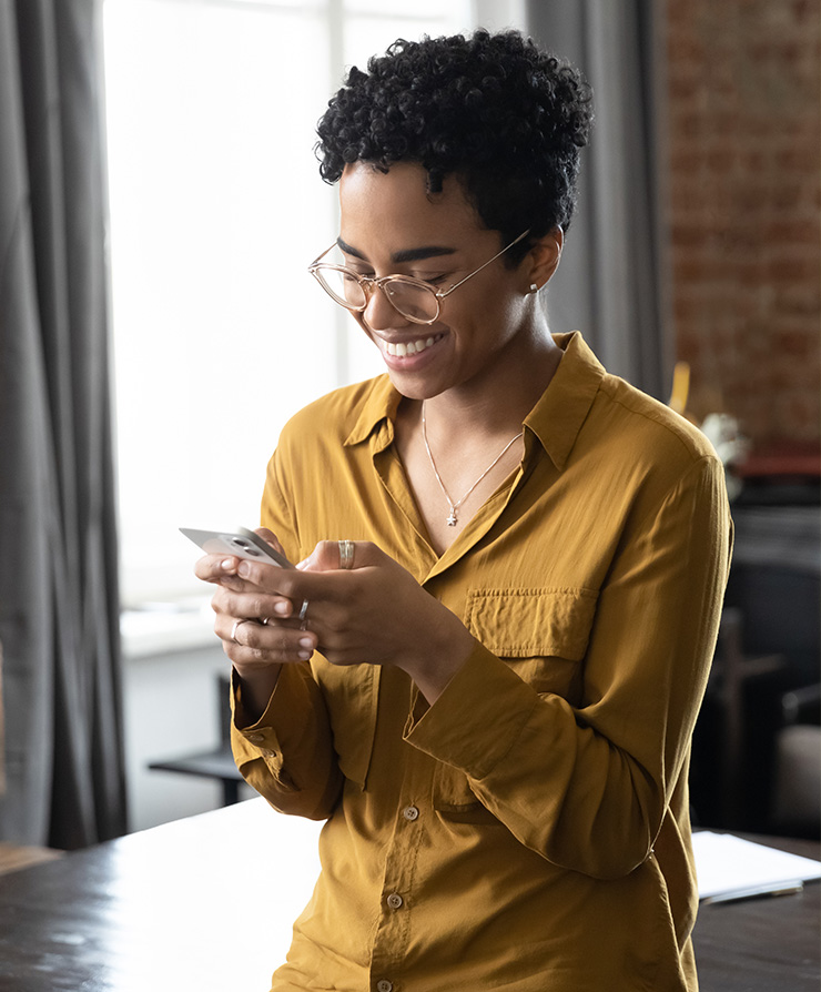 Young woman smiling while looking at phone