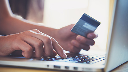 Close up of hands entering credit card information on laptop for online shopping