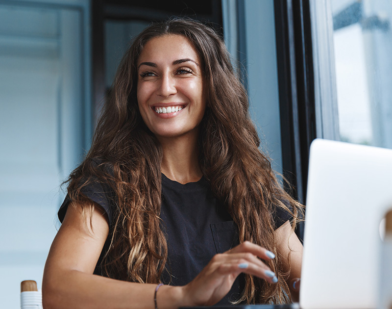 Happy woman looking away from computer