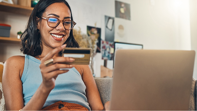 Happy young woman entering credit card info for online purchase