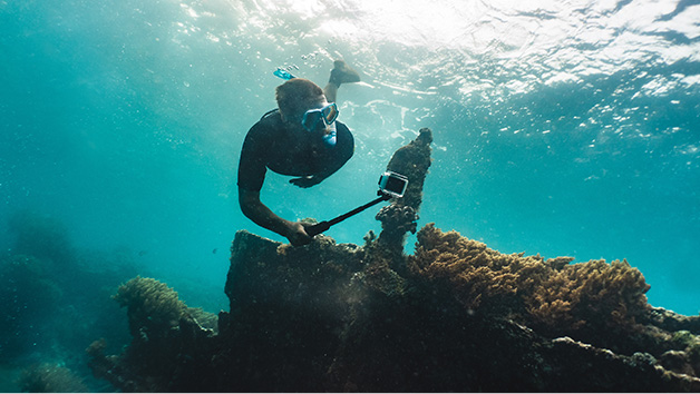 Man snorkeling deep underwater with waterproof camera