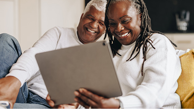 Mature African-American couple looking at laptop together at home