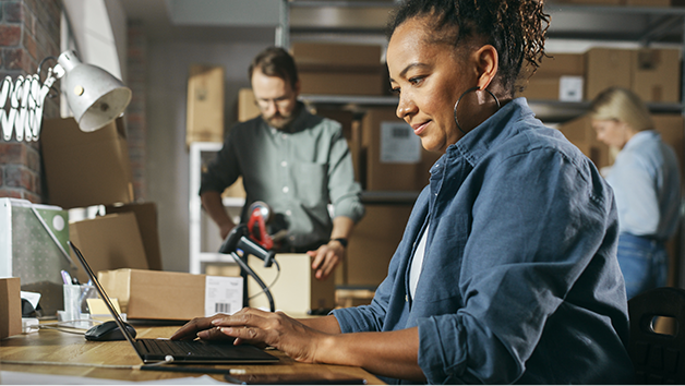 Small business woman using laptop in eCommerce warehouse