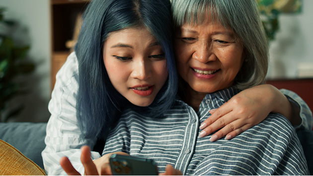 Young woman helping grandmother use mobile phone