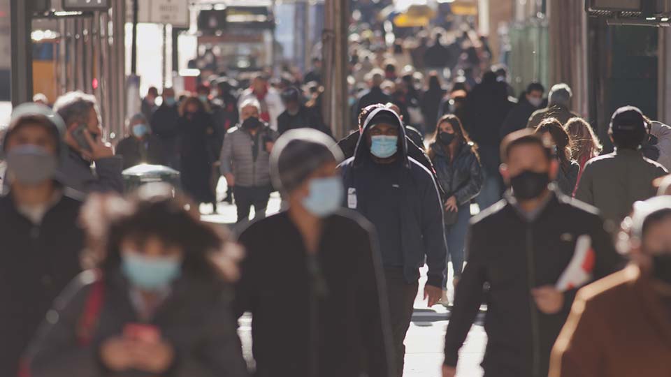 Crowd of masked people crossing the street during the pandemic