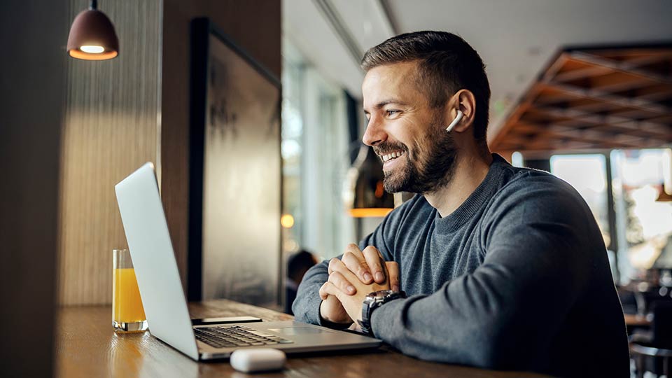 Man taking webinar using laptop at coffee shop