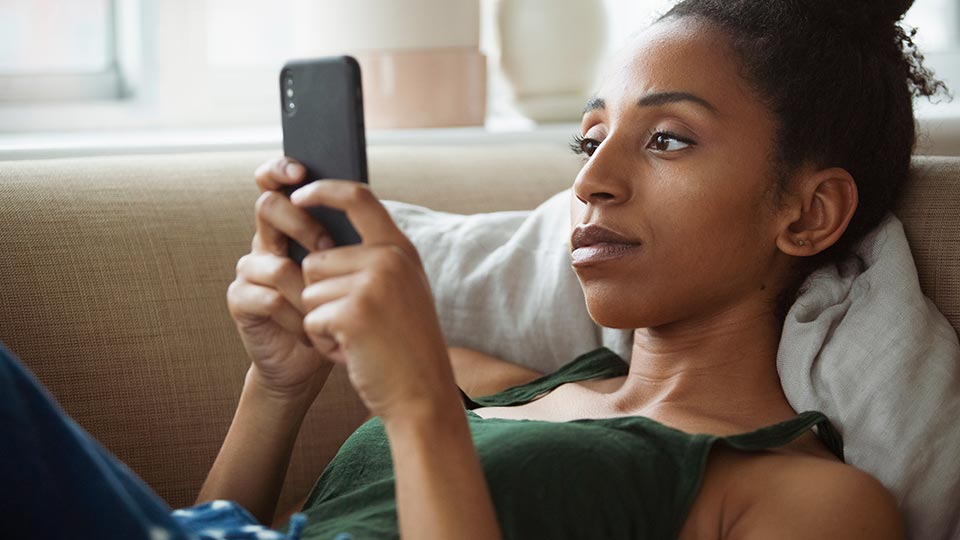 Serious woman looking at phone on couch
