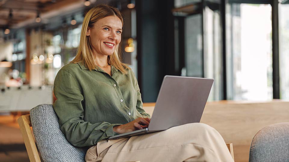 Woman on couch smiling with laptop
