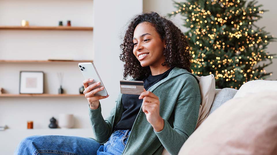 Woman online shopping with credit card and phone during the holiday season